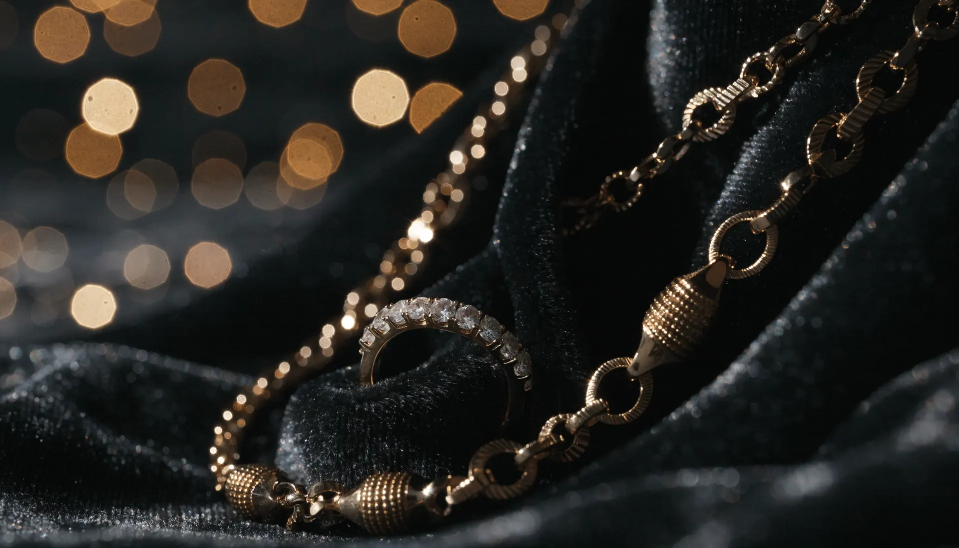 Gold necklace and diamond ring on dark velvet with warm bokeh